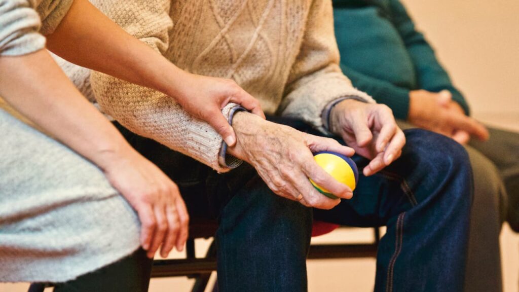 pexels-photo-339620 An elderly person receives support from a caregiver, holding hands indoors, showcasing compassion.